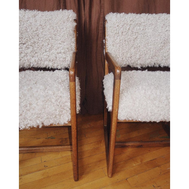 A pair of mid-century oak armchairs featuring clean architectural lines and newly upholstered seats and backs in a plush...