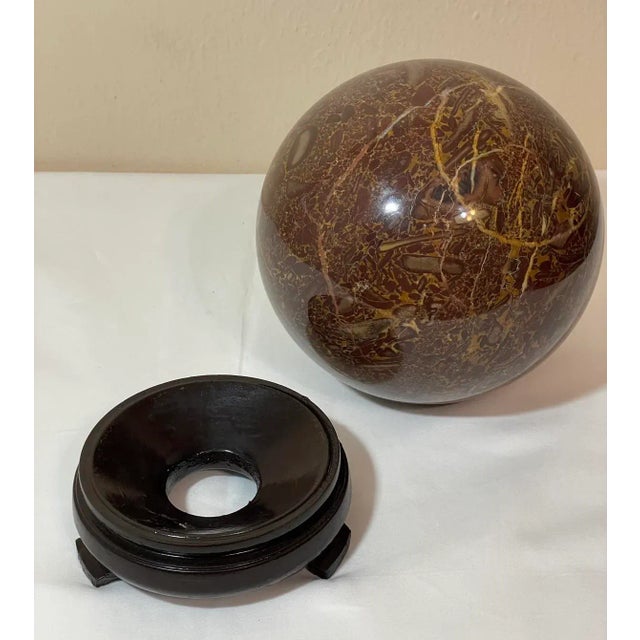 Vintage large marble ball sphere orb on lacquered wood display stand. The marble is chestnut brown with caramel/amber,...