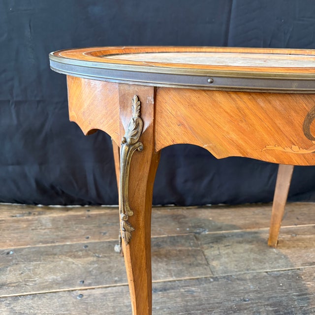 Elegant antique French Louis XV marble-top table featuring an oval inset marble top framed by richly figured walnut and...