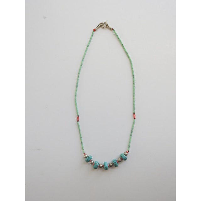 Late 20th century dainty turquoise beaded necklace with tiny turquoise heishi beads and coral bead accents. Hook and loop...