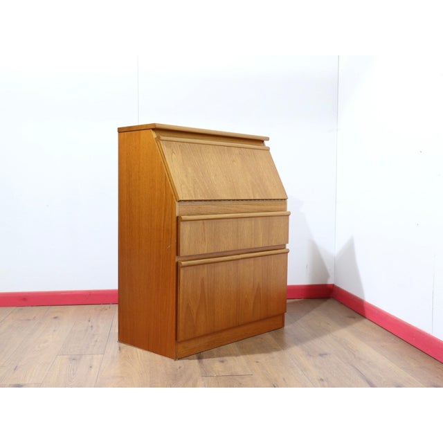 Discover a beautiful small teak secreataire that perfectly embodies the elegance and functionality cherished by Mid...