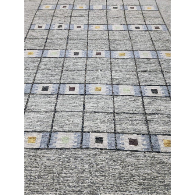 This hand-knotted modern Swedish-style rug, crafted from gray wool, features a striking geometric design complemented by...