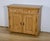 This century-old sideboard is a solid pine piece of furniture featuring two drawers at the top, each with a round white...