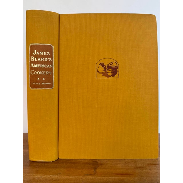 First edition copy of James Beard's American Cookery, published in 1972. Hardcover is covered in yellow fabric with gold...