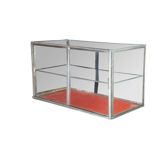 Vintage two tiered desktop curio display case featuring rectangular form with a fixed central shelf and two sliding doors....