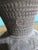 This is a handmade clay vessel that has a wide flaring rim and bulbous body and features densely stamped geometric...