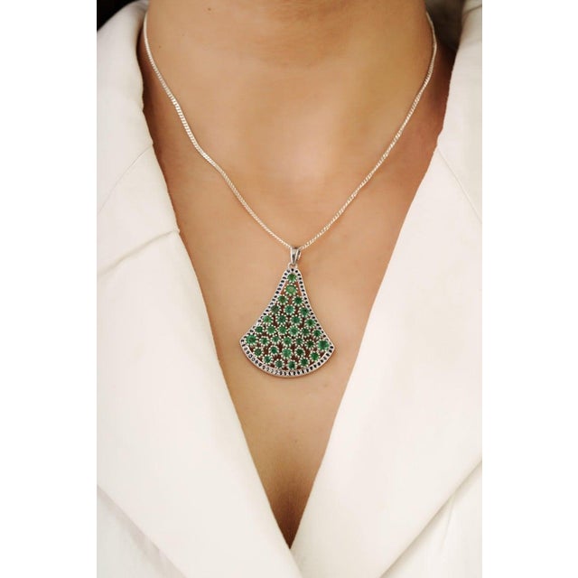 This pendant is crafted in 925 sterling silver and features a refined cluster design set with natural emeralds accented by...