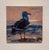 This oil painting depicts a solitary sea gull standing against a soft, atmospheric backdrop of a sunset. The artist...