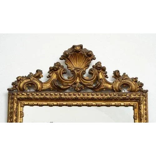 Antique Louis XVI Neapolitan mirror in gilded and carved wood dating back to the mid-18th century. The mirror is set in a...