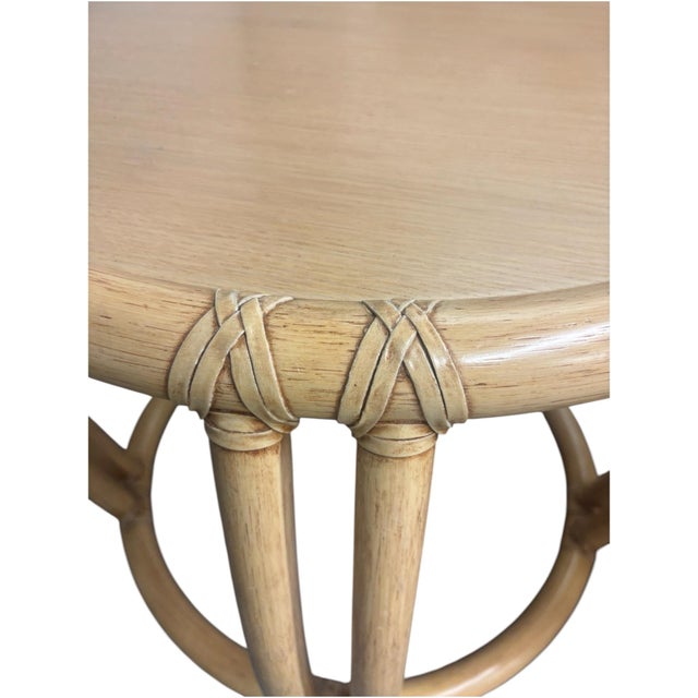 Small round tables made of curved wicker bamboo-look wood, with a light wood top. Natural tan color.