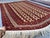 This striking Turkmen Bokhara rug presents a diagonal zigzag lattice of elongated diamond compartments in warm rust and...