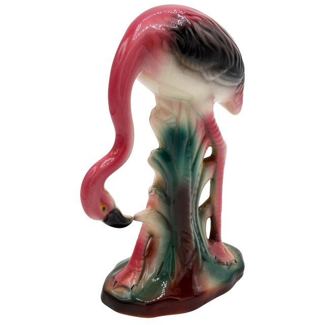 Mid-century pink and green flamingo ceramic figurine grazing on a grassy field . The statue depicts a pink flamingo with...