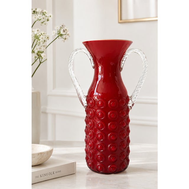 Striking vintage red glass vase featuring two sculptural clear glass handles, in the distinctive style of Italian mid-...