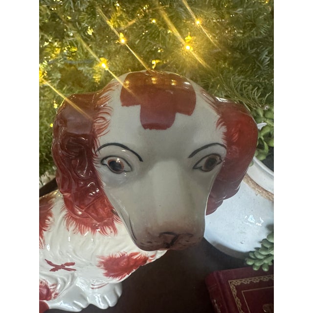 Antique English Staffordshire-style spaniel figurine modeled in a seated pose, finished in a rich iron-red and soft cream...