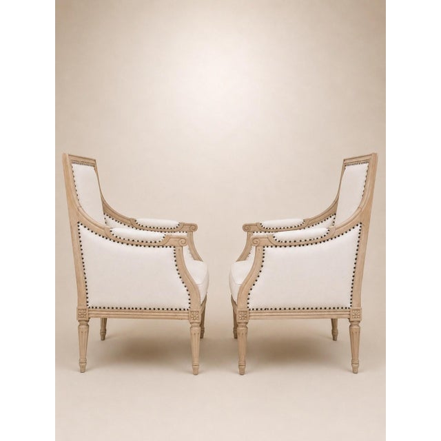 Pair of Louis XVI style bergère armchairs in solid carved beechwood, likely a 20th-century reproduction in the...
