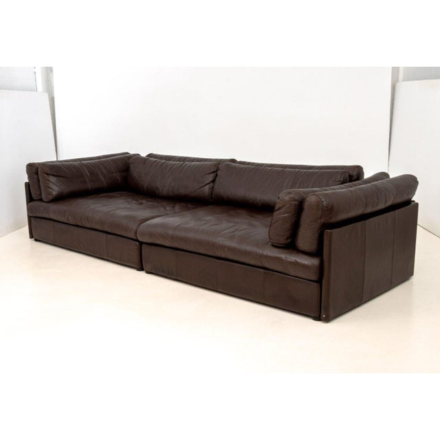 Stendig Brown Leather Three-Seat Sofa, in two parts with six cushions, with label. 26" H x 111" W x 45" D; seat: 14.5" H....