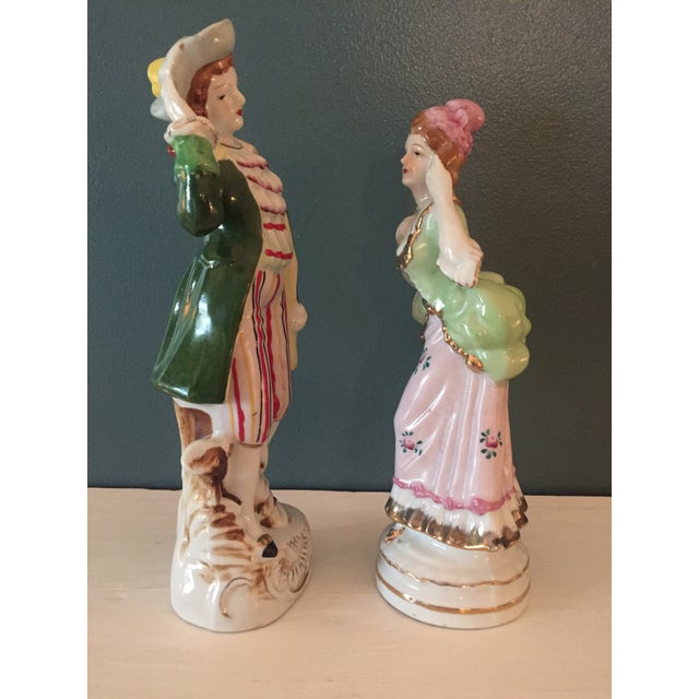 Beautiful pair of figurines, a man and woman, in colorful British colonial dress. I believe these were made between...