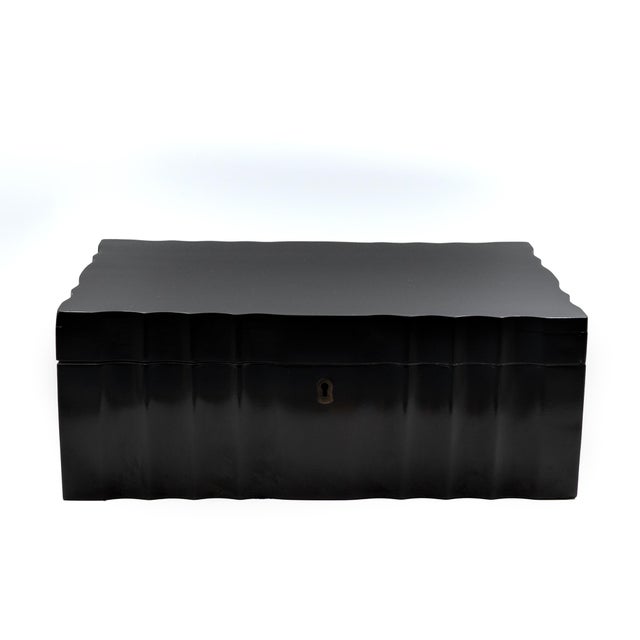 A large-scale box of serpentine form, the exterior in polished ebony, the sides and front cut in a continuous undulating...