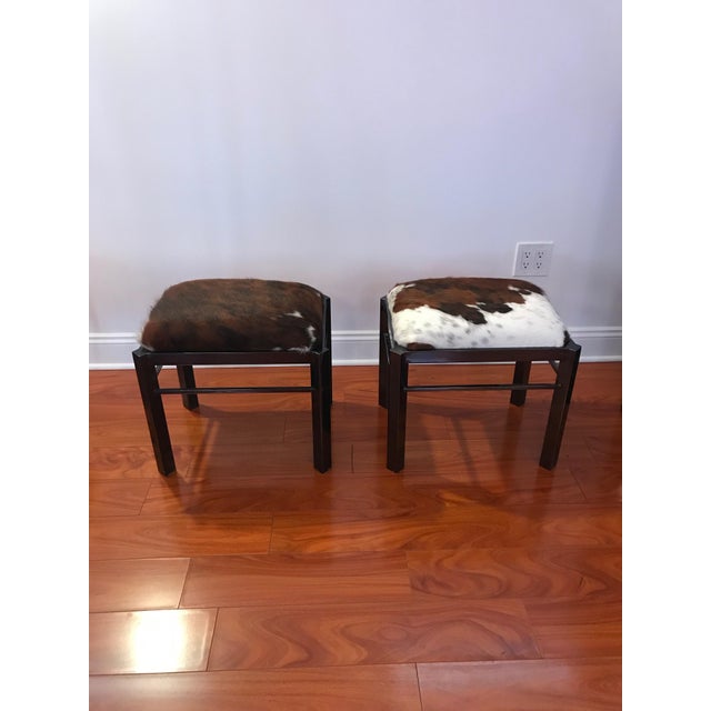 Beautiful pair of Mid-Century Modern benches upholstered with cow hide. With black metal frame and upholstered cowhide top.
