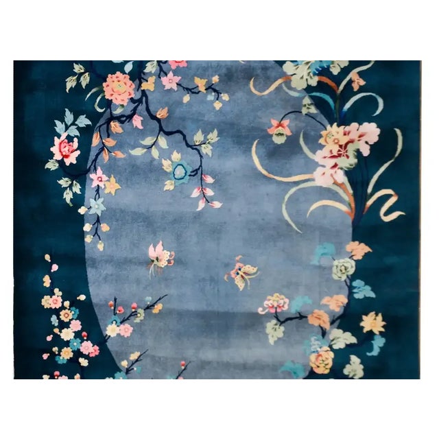 A beautiful early 20th century Chinese Art Deco rug with a dark indigo border surrounded a gray oval medallion overlaid...