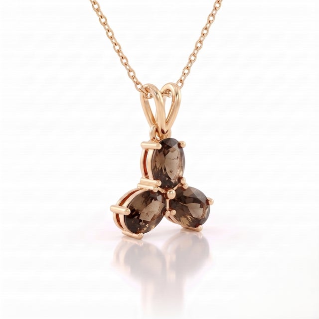 An earthy three-stone design featuring oval-cut natural smoky quartz arranged in a graceful trefoil formation, secured in...