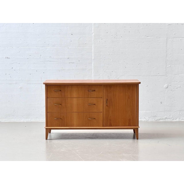 This elegant 1950s sideboard impresses with its clean, mid-century design and harmonious proportions. The warm wood finish...