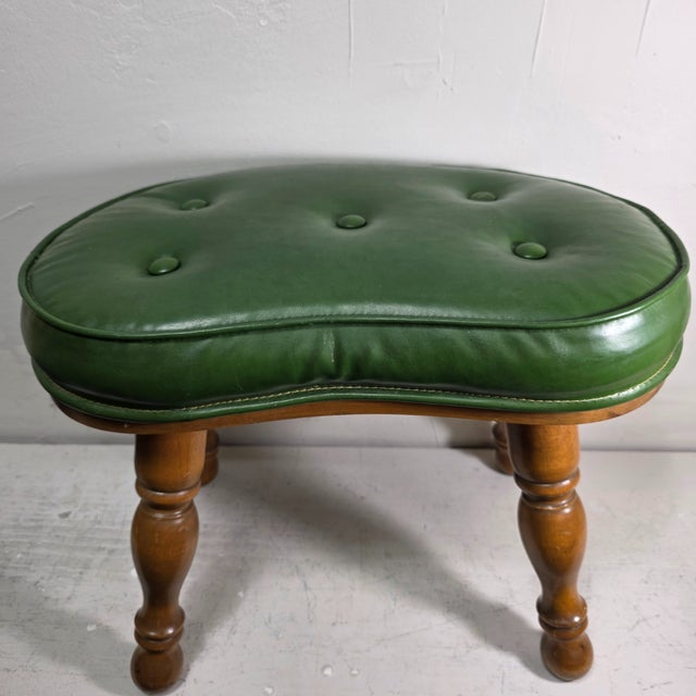 A well-proportioned mid-century vintage footstool featuring a sculptural kidney-shaped top upholstered in green vinyl,...