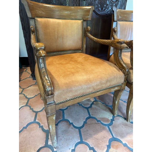 Old pair of empire style camel colored leather chairs. Nail head trim, distressed carved frames, dolphin carved arms. Deep...