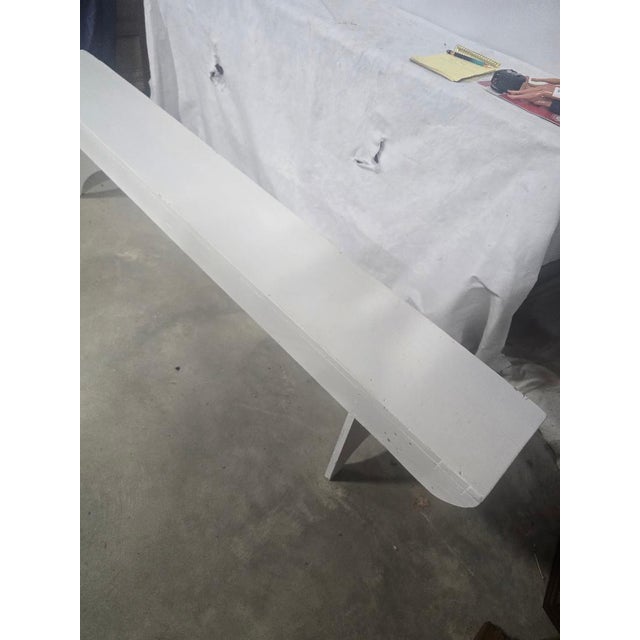 Long farmhouse-style solid wood bench with a simple backless design, white painted finish, rounded ends, and shaped...