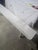 Long farmhouse-style solid wood bench with a simple backless design, white painted finish, rounded ends, and shaped...