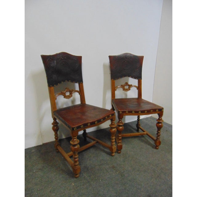A pair of Italian Renaissance style side chairs. , fancy embossed leather seats and backs , large brass rack trim , walnut...