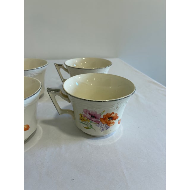 A set of 6 vintage teacups in soft ivory china, decorated with a painterly floral motif of orange and pink poppies, yellow...