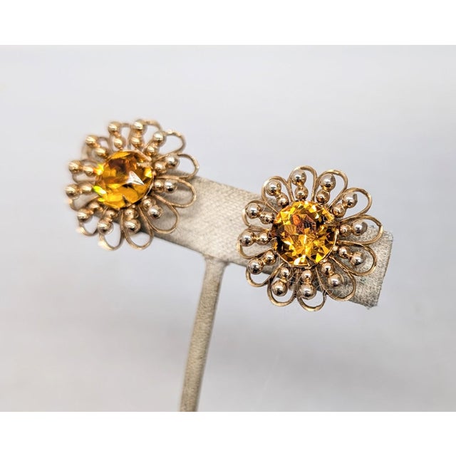 1950s goldtone openwork with prong set round faux-citrine center flower clip earrings. Marked "Napier" in the dip of the...