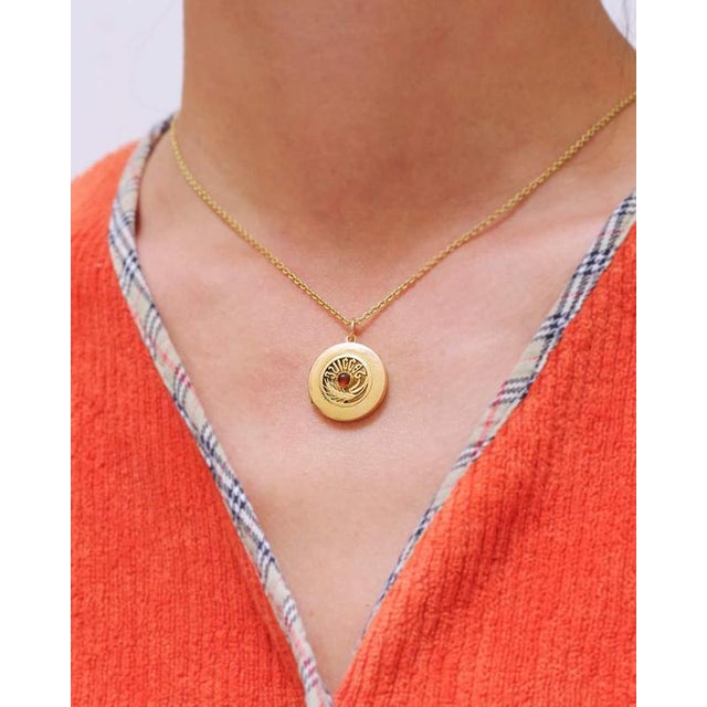 Art Nouveau July locket pendant in 18 karats gold. A circular photo locket centered with an orange glass cabochon,...