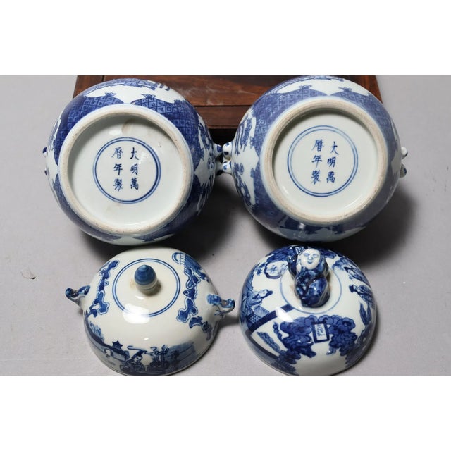 A pair of vintage Chinese lidded blue and white pots. The bases are identical, but the lids differ.