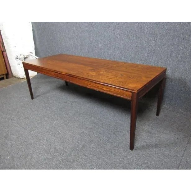 Absolutely stunning mid-century rosewood coffee table. A large tabletop, bold lines, and tapered legs show off the wood...