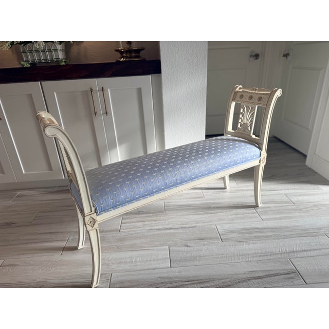 Elegant French Directoire style painted bench featuring graceful carved details and soft light blue upholstery. A timeless...