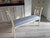 Elegant French Directoire style painted bench featuring graceful carved details and soft light blue upholstery. A timeless...
