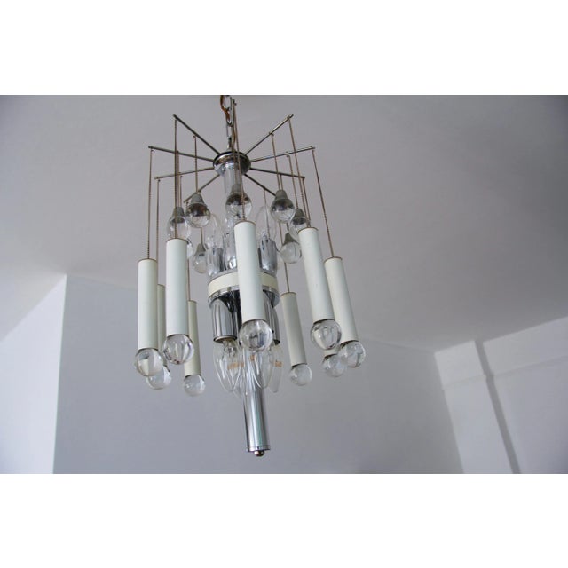 Extraordinary playful Chandelier from the 1970s, 8 lamps that radiate up and down, thin chains carry glass balls, in which...