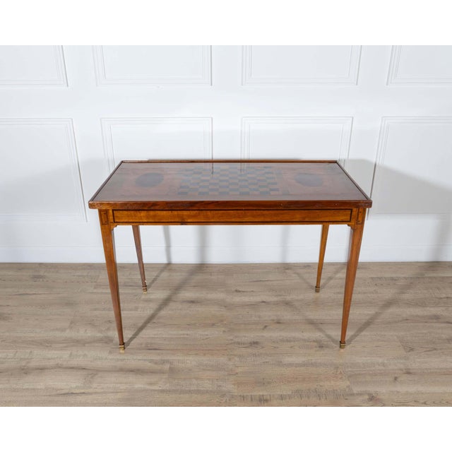 This late 18th-century tric trac table is constructed in varnished marquetry with a removable reversible top. One side...