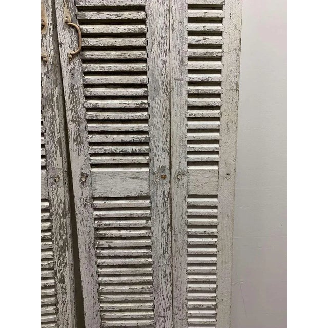 Lovely pair of two part decorative french shutters in historic paint from the early 1900s. They are both in two hinged...
