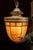 Hanging pendant lantern featuring a warm amber slag glass shade segmented by dark metal leading, forming a tapered, acorn-...