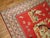 A pictorial rug depicting a dog floating around different humans, animals, and figures on a red ground. 3'9'' x 6'2''