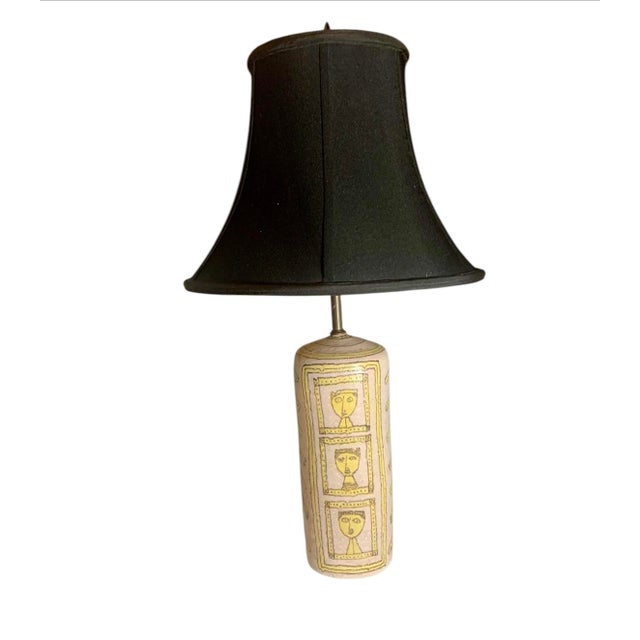 Substantial stoneware base with long neck in soft yellow and pale purple , design is portraits with arrows signed on...