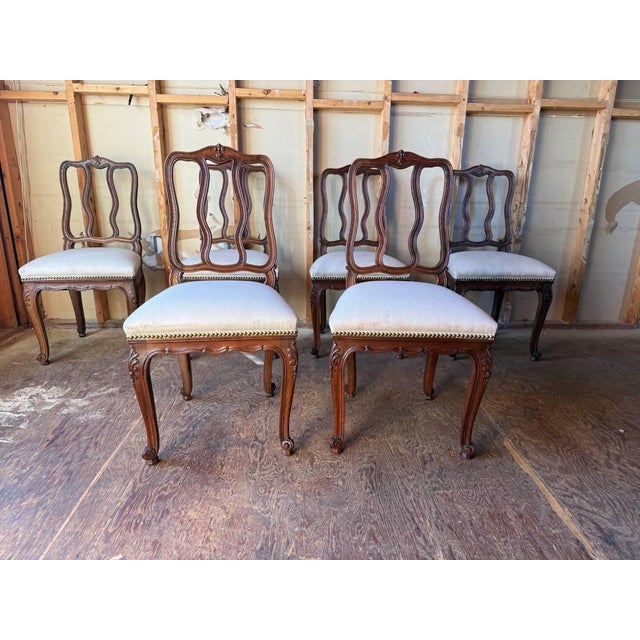 Antique French provincial style Carved Oak Dining Chairs Each features an openwork back with pierced scroll motifs and...