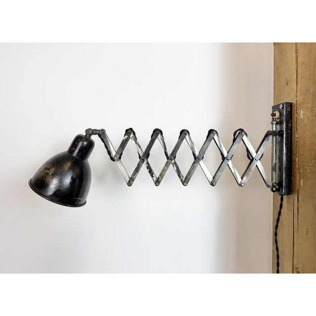 This vintage industrial scissor lamp was produced in former czechoslovakia during the 1950s. The lamp has a black...