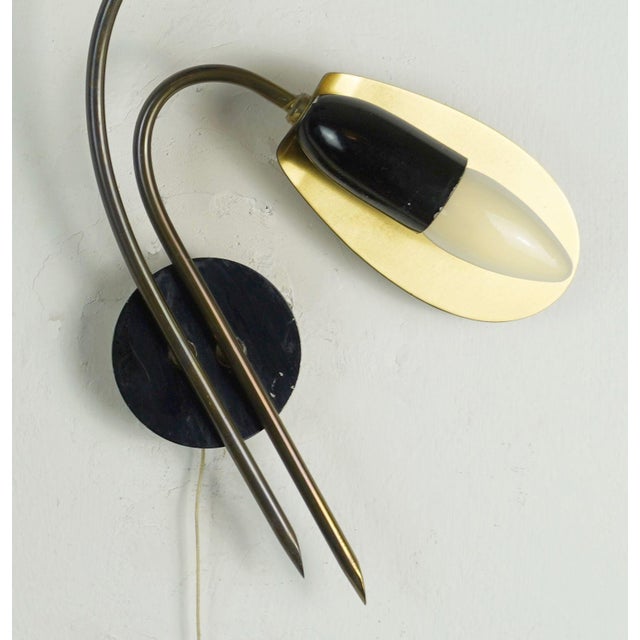 A beautiful and decorative pair of vintage wall lamps from the 1950s. The wall brackets are brass with black lacquered...