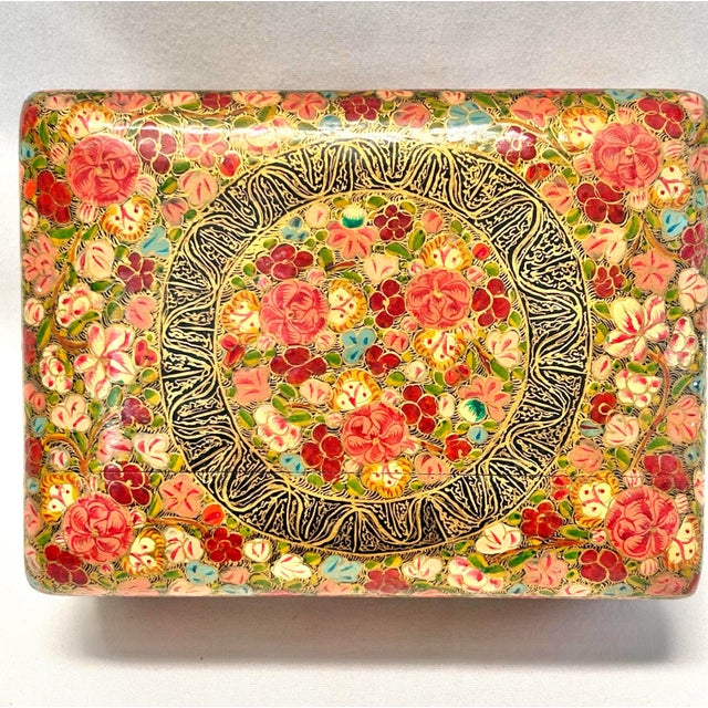 A large vintage Kashmiri papier-mâché box densely decorated with hand-painted flowers, scrolling foliage and intricate...