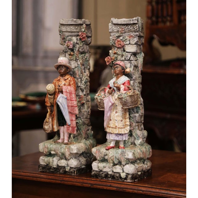 A richly modeled pair of antique French barbotine vases, each conceived as a picturesque architectural scene with a finely...