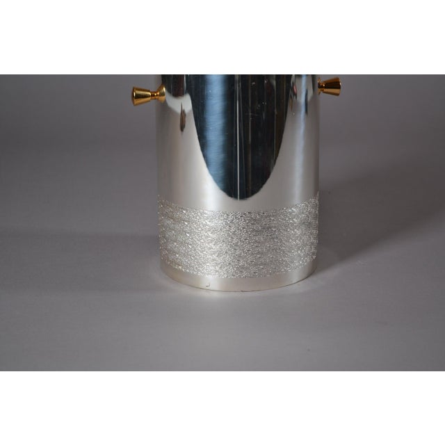 1980s metal wine cooler with a cylindrical silver-toned body, a textured decorative band around the lower section and two...